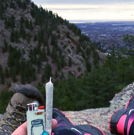 7. Se for possível, fume em ambientes externos pessoa segurando um baseado e um isqueiro em uma montanha